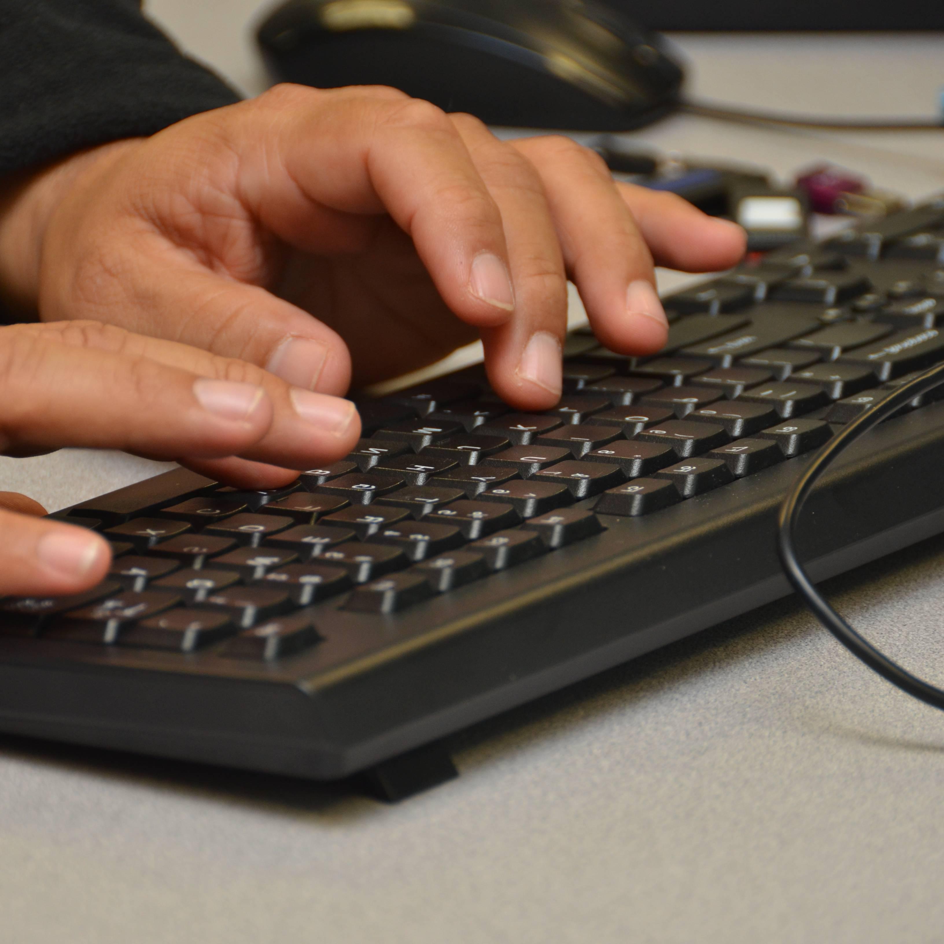 student typing on a keyboard